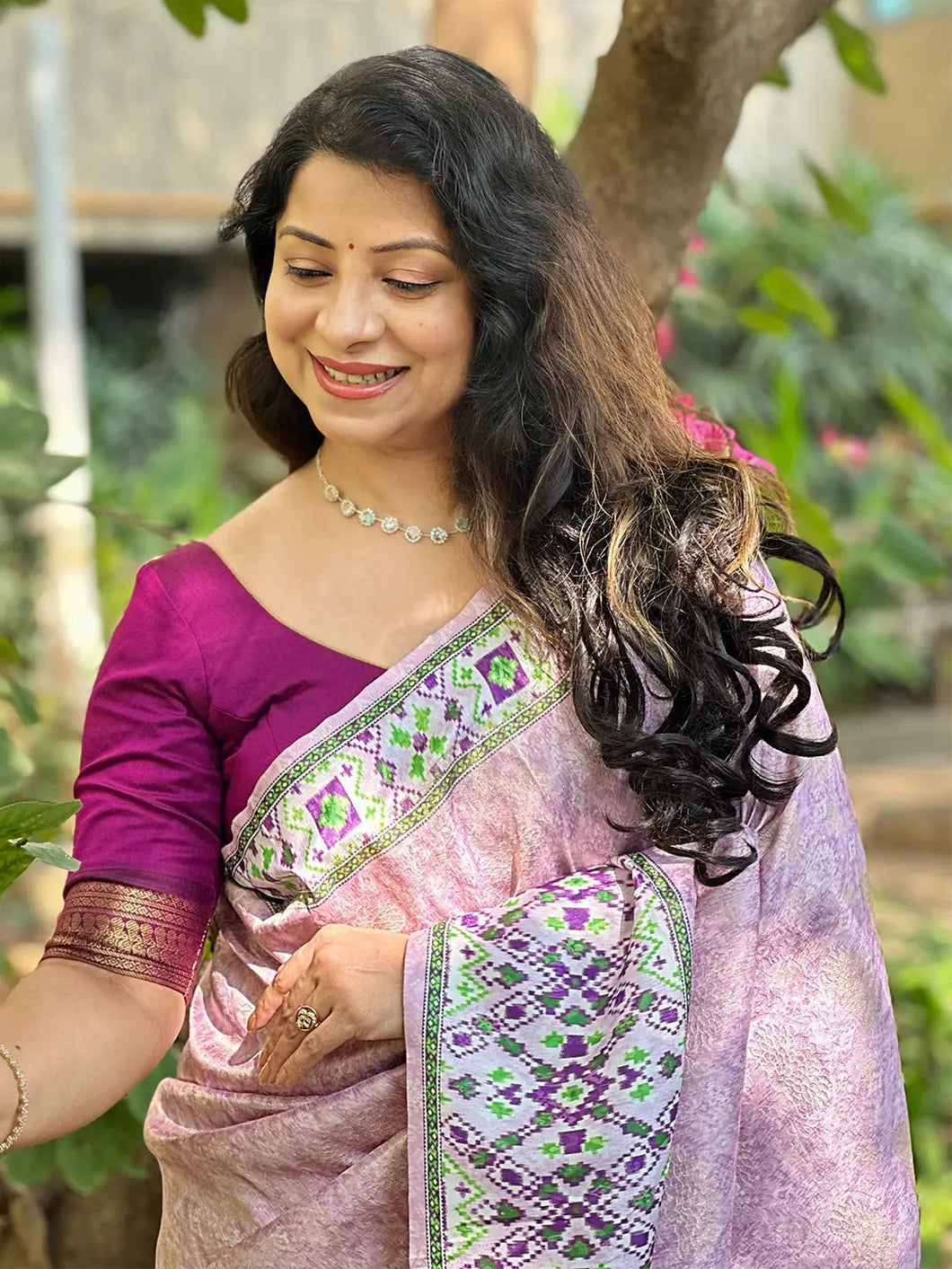 Woman in pink Kanjivaram saree with Patola print outdoors